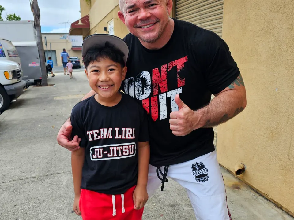 A young student with his coach at the door of Darcio Lira BJJ