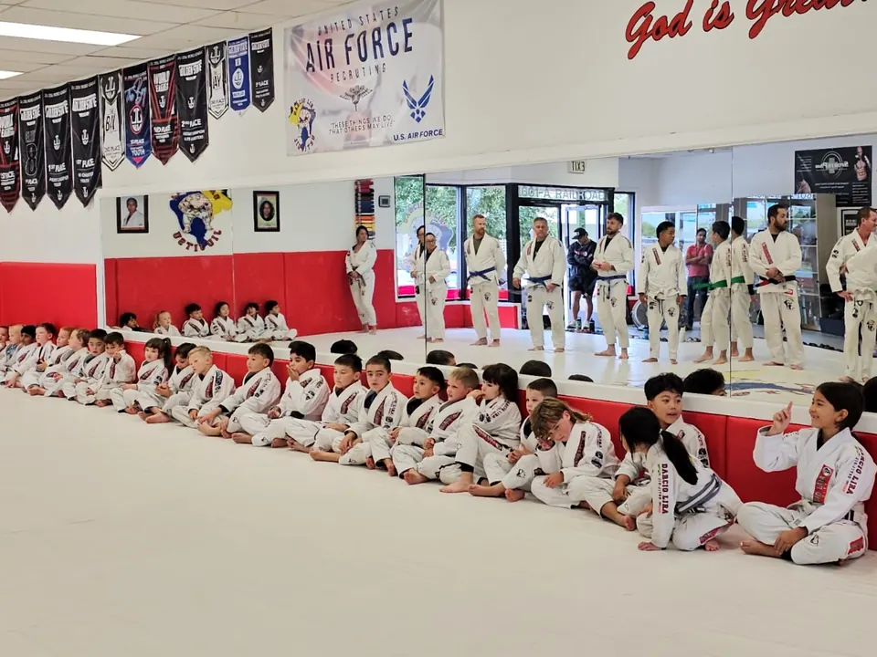 The whole kids class seated on the mats, seen from the sidelines at Darcio Lira BJJ